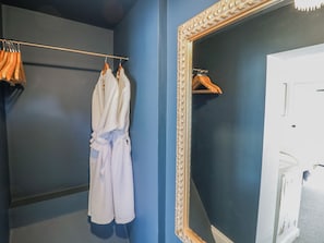 Un baño con un espejo grande, un perchero con toallas y una bata colgada en la pared.