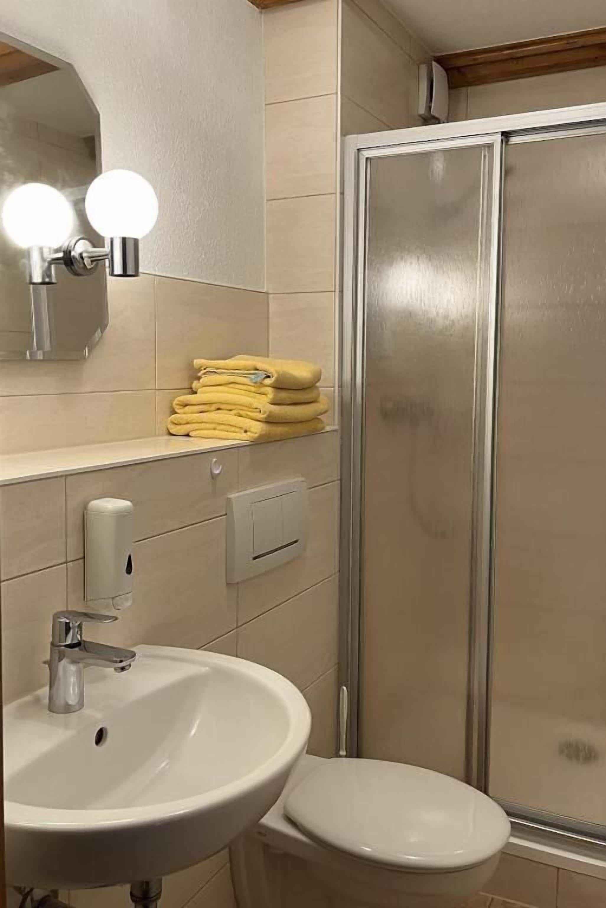 A bathroom with a sink, toilet, and a glass shower enclosure.