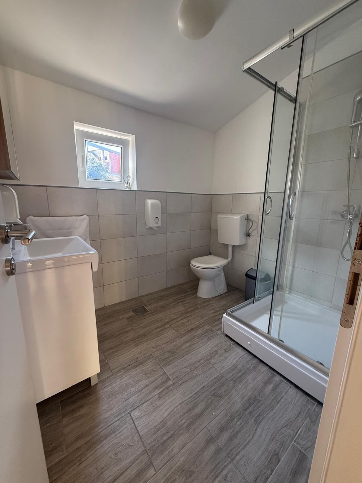 Un baño moderno con inodoro, cabina de ducha de vidrio y lavabo.