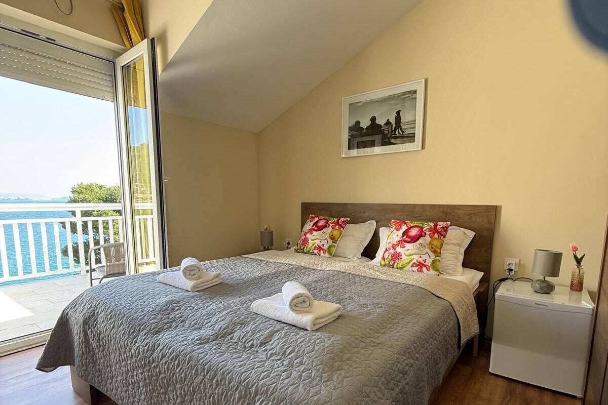 A bedroom with a large bed, a nightstand, a lamp, and a picture on the wall.