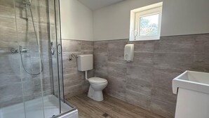 A bathroom with a glass shower enclosure, a toilet, and a sink. - Adrian's Beach House by Max Gastro (Marina)