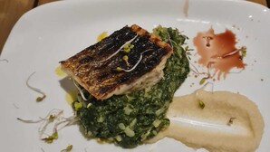 A white plate with a piece of grilled fish, green vegetables, and a creamy side dish. - Adrian's Beach House by Max Gastro (Marina)