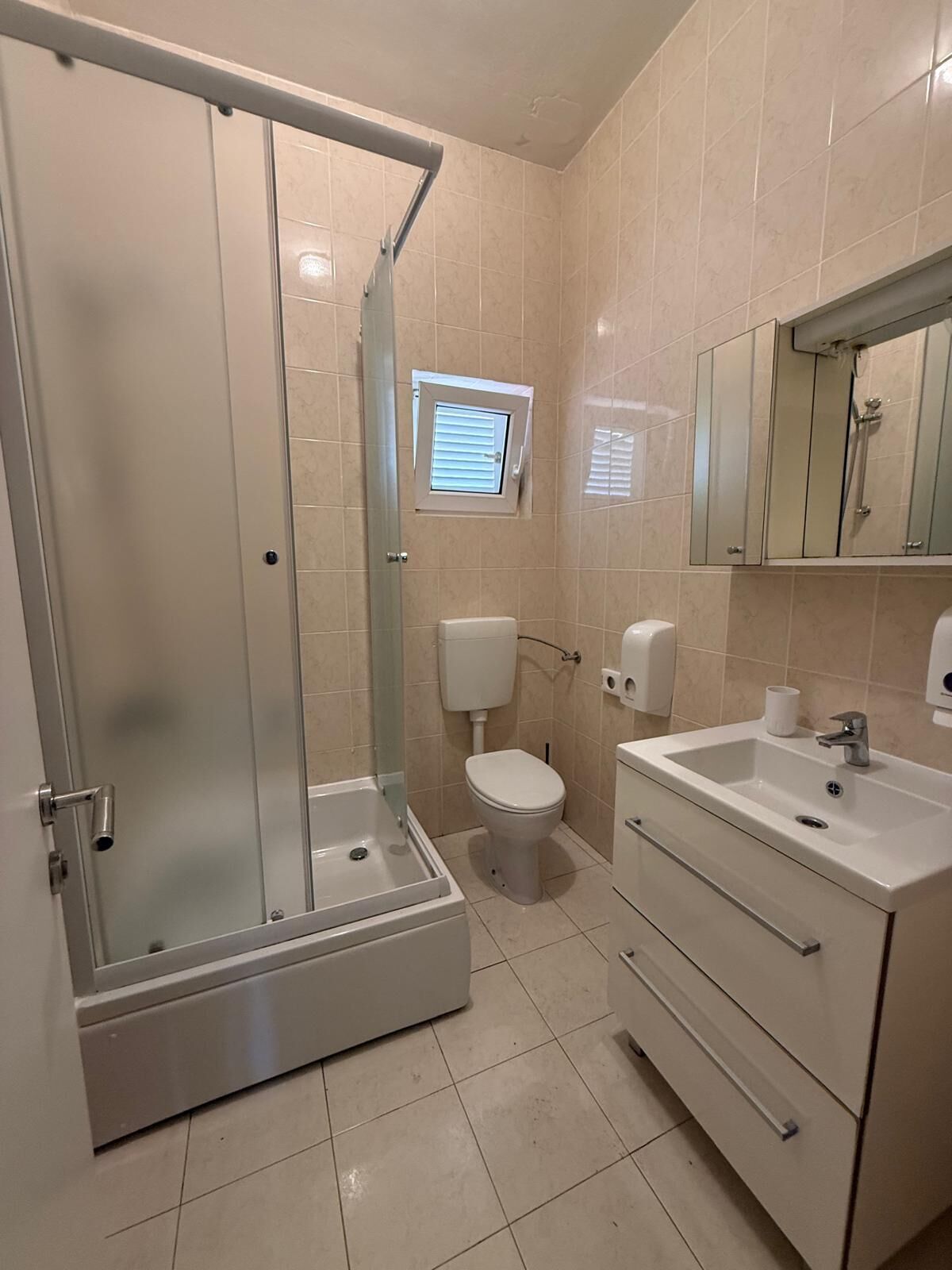 Un baño con ducha de vidrio, inodoro, lavamanos y espejo.
