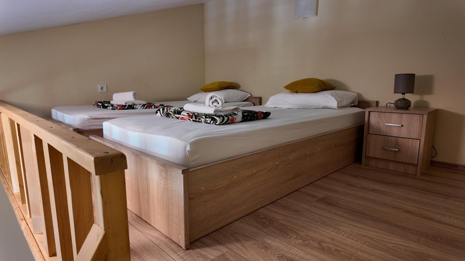 A bedroom with a wooden bed, two bedside tables, a nightstand, and a lamp.