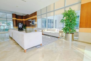A modern lobby with a reception desk, seating area, large windows, and a potted plant. - Free Housekeeping Visits During Your Stay - Stayshort - Fancy 1-bedroom Apartment Sleeps 4 in Dubai Marina (Dubai)