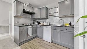 Une cuisine moderne avec des meubles gris, des appareils en acier inoxydable et un plancher en bois.