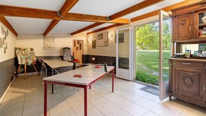 Une pièce comprenant une table de ping-pong, une table à manger et un buffet.