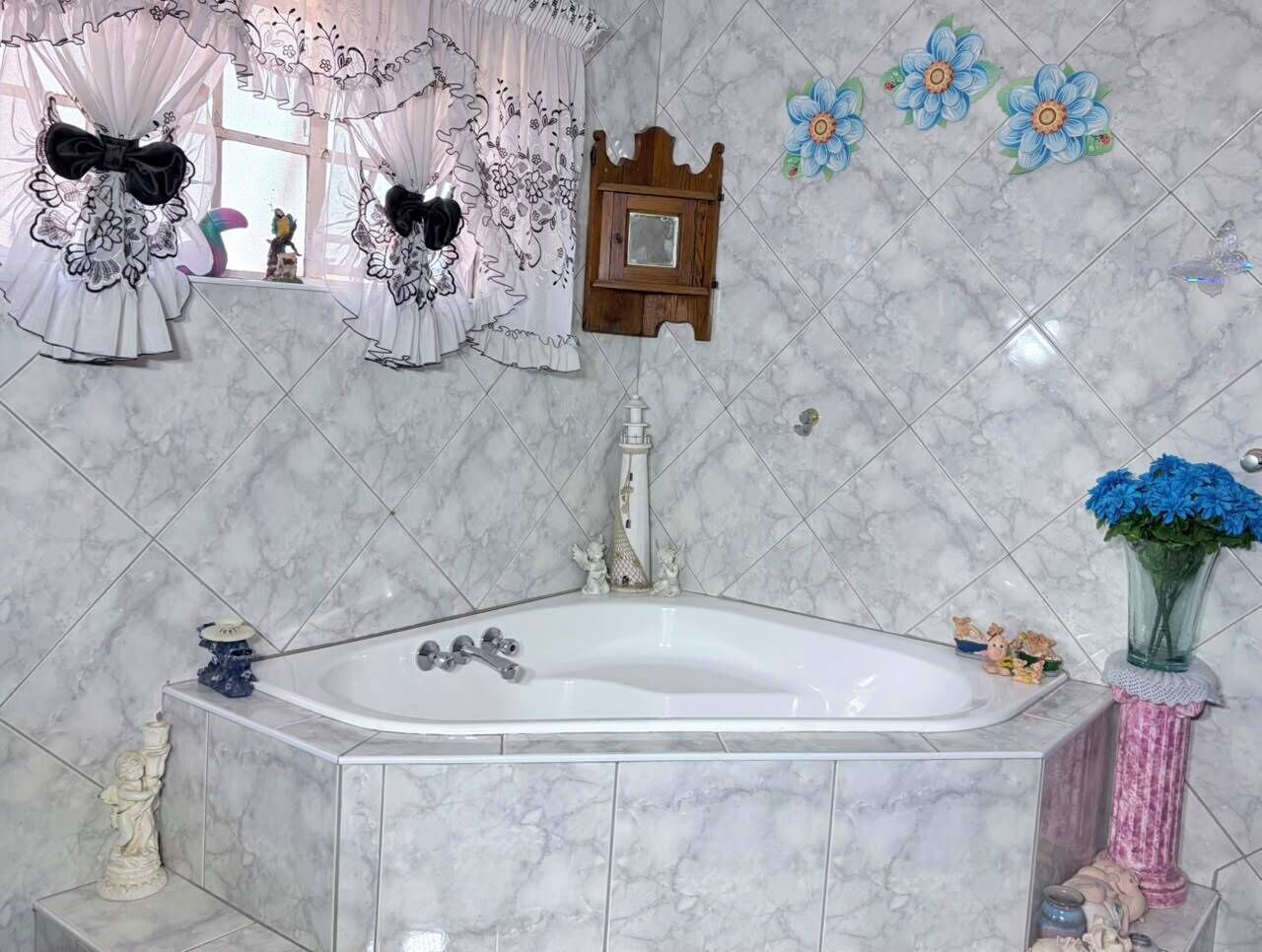 Een badkamer met een marmeren vloer, een badkuip, een houten kastje en decoratieve bloemen.