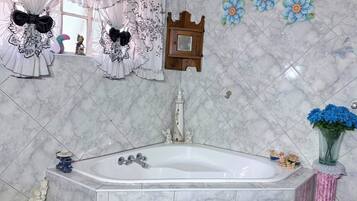 Een badkamer met een marmeren vloer, een badkuip, een houten kastje en decoratieve bloemen.