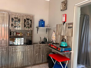 Une cuisine compacte avec des meubles de rangement en bois, un évier, une cuisinière à gaz et une table pliante.