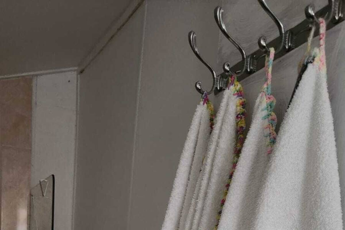 A bathroom with a white towel rack holding three white towels with colorful edges.