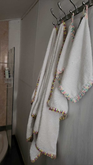 Un baño con un toallero blanco que sostiene tres toallas blancas con bordes coloridos.