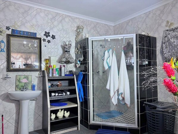 A bathroom with a sink, mirror, vanity, and a shower with glass doors.