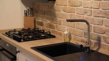 Une cuisine équipée d’une cuisinière à gaz, d’un évier et d’un mur en briques.