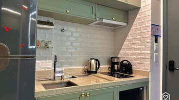 A kitchen with a built-in microwave, a coffee maker, and a kettle on the countertop.