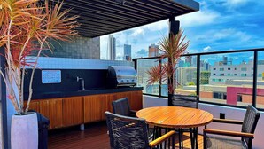 Un bar sul tetto con griglia, posti a sedere e vista sulla città.