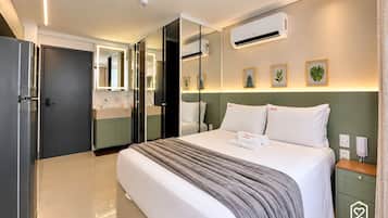 A hotel room with a bed, bedside table, nightstand, and a large mirror.