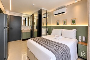 Una habitación de hotel con una cama, mesita de noche y un espejo grande.
