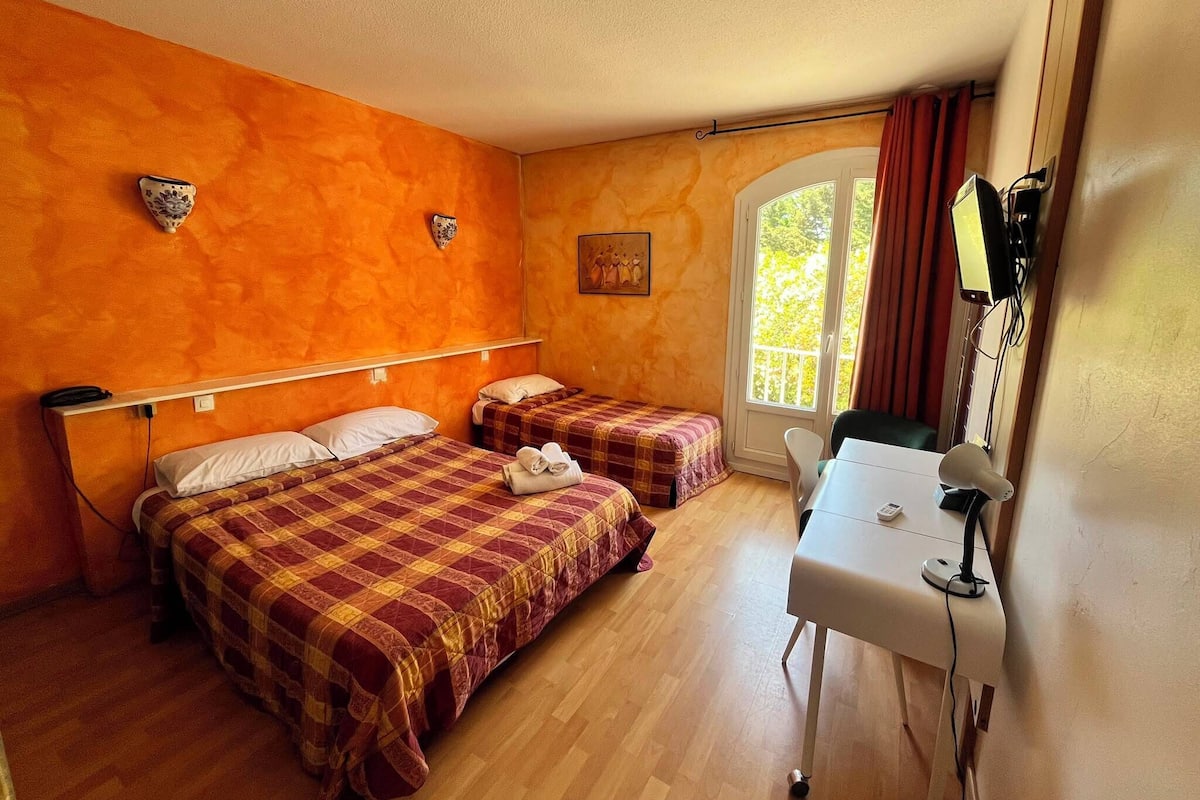 Une chambre avec deux lits, un bureau et une fenêtre avec des rideaux.