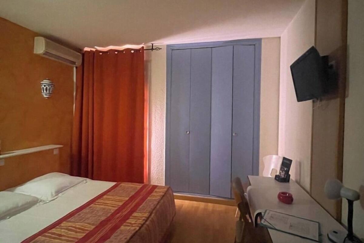 Une chambre d’hôtel comprenant un lit, un bureau, une chaise, une télévision et une armoire.