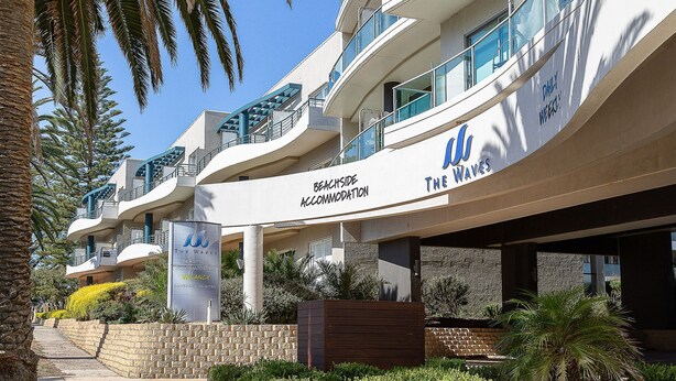 A beachfront hotel with balconies, a sign indicating beachside accommodation, and a sign for conference facilities. - Bayview on The Esplanade (Cowes)