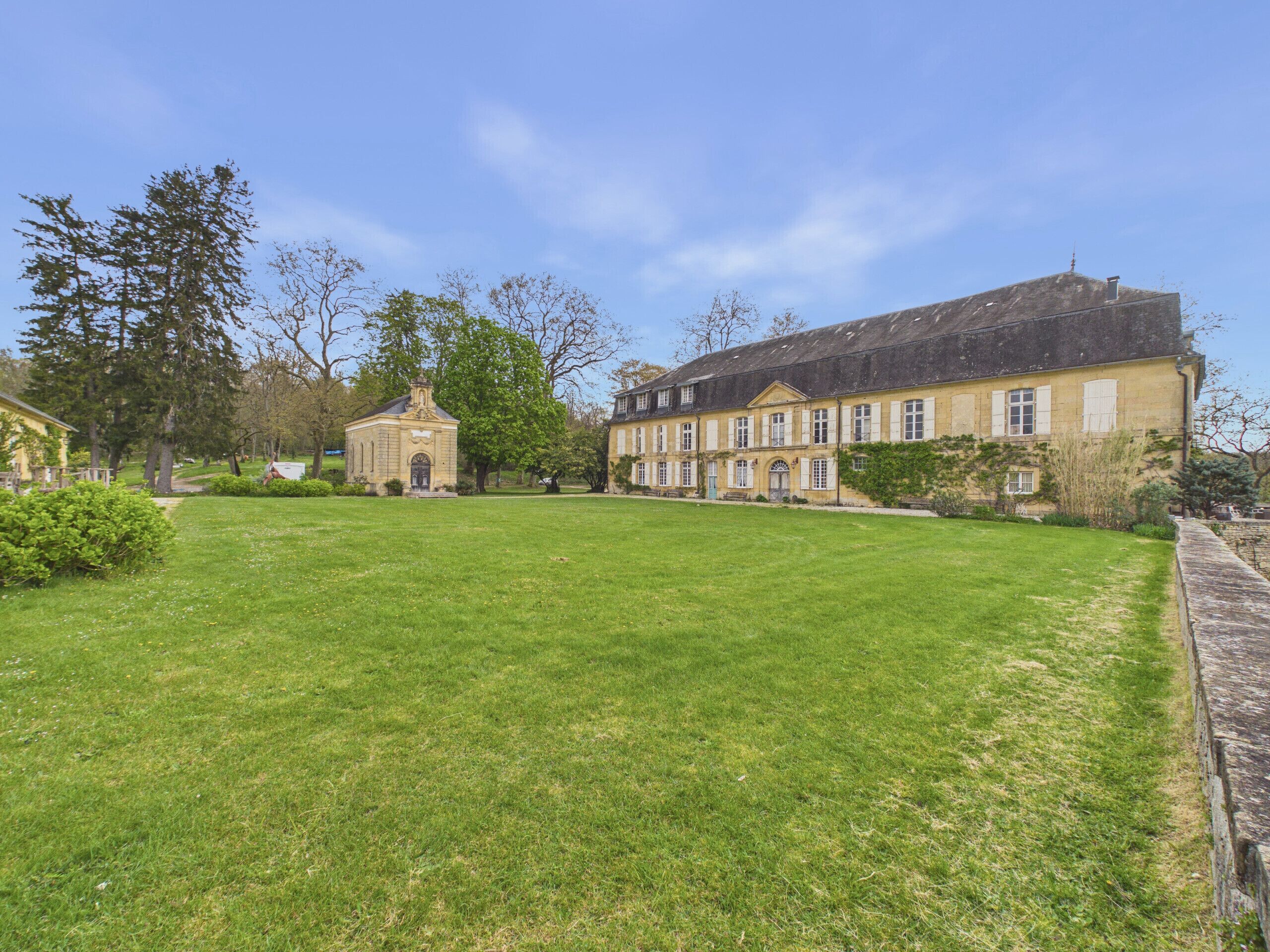 A large, historic building with a symmetrical facade, a central entrance, and a well-maintained lawn.