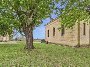 A building with a large tree in front, a grassy area, and a clear sky. - Large 11-guest cottage, shared pool & nature (Fanlac)