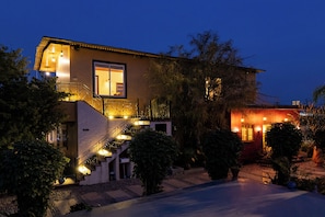 Una casa de dos pisos con escaleras, un ventanal grande e iluminación exterior.
