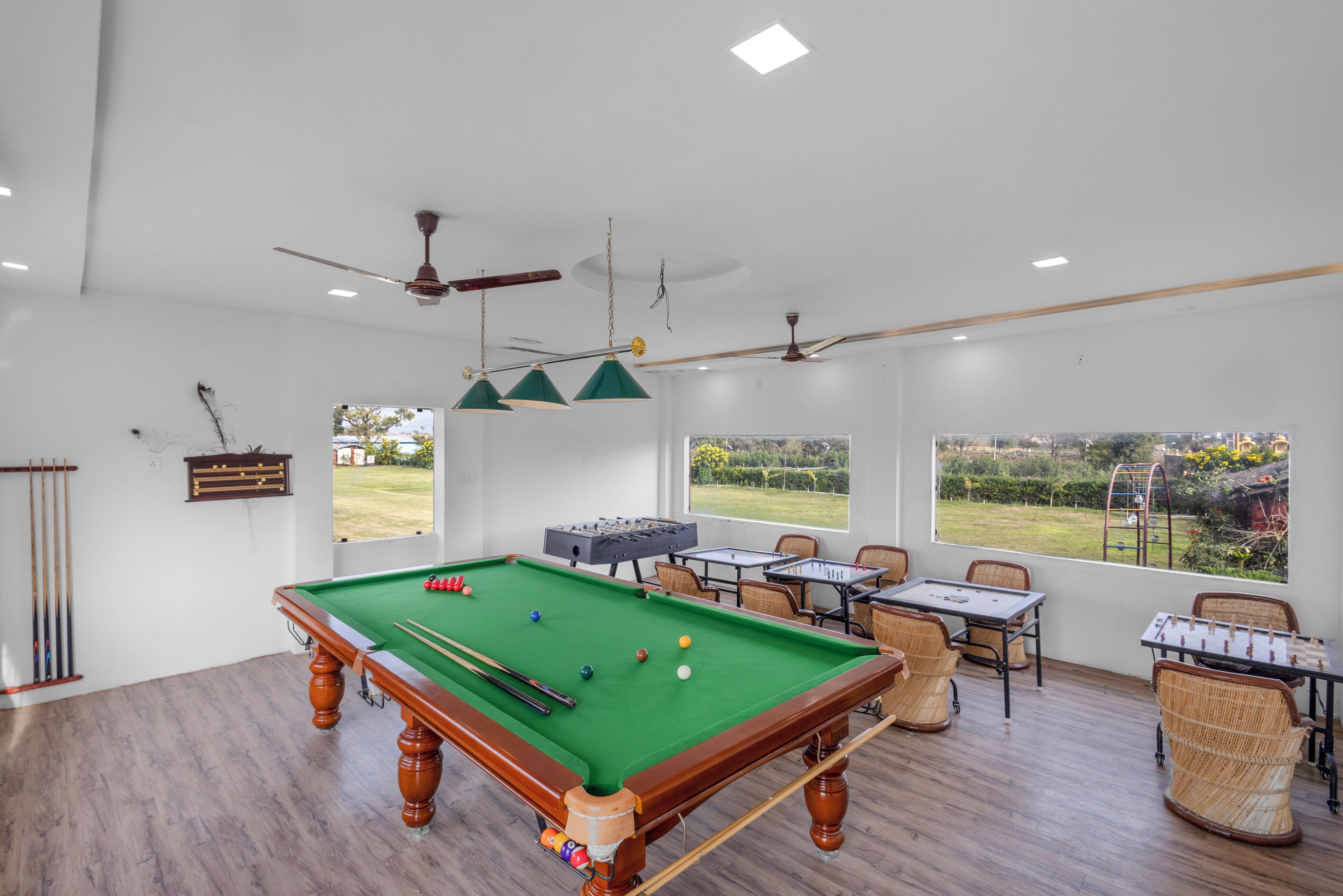 A pool table with surrounding chairs and tables, a ceiling fan, and a view of the outdoors.