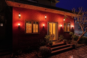 Un bâtiment en briques avec une façade rouge, une porte en bois et des marches menant à l’entrée.