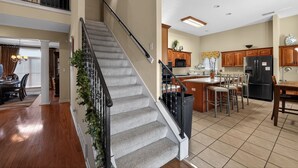 Eine geräumige Küche mit einer zentralen Kochinsel, Holzschränken und einem schwarzen Kühlschrank.