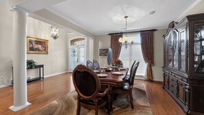 Ein Esszimmer mit Holztisch, Stühlen, einer Chandelüster und einem großen Schrank.