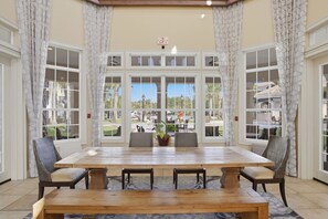 A dining area with a large table, chairs, and a view through large windows. - Poolside Resort Condo- CLOSEST To Theme Parks!! (Orlando)