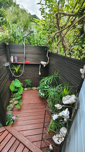 A wooden deck with a metal rack holding seashells, surrounded by lush greenery and a wooden fence. - Between sea and mountains in a lush tropical garden with heated pool (PITON SAINT LEU)