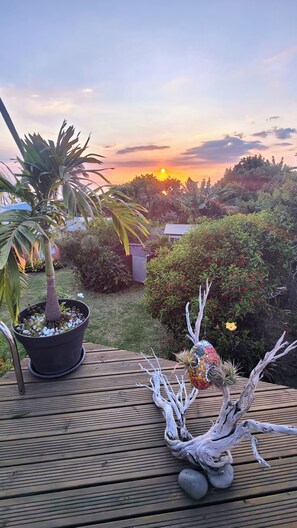 A garden with a wooden deck, a potted plant, and a decorative tree branch. - Between sea and mountains in a lush tropical garden with heated pool (PITON SAINT LEU)