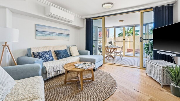 A modern living room with a sofa, coffee table, and a television. - Riviera 102: 2  BR, 2  BA Apartment in Port Macquarie, Sleeps 4 (Port Macquarie)