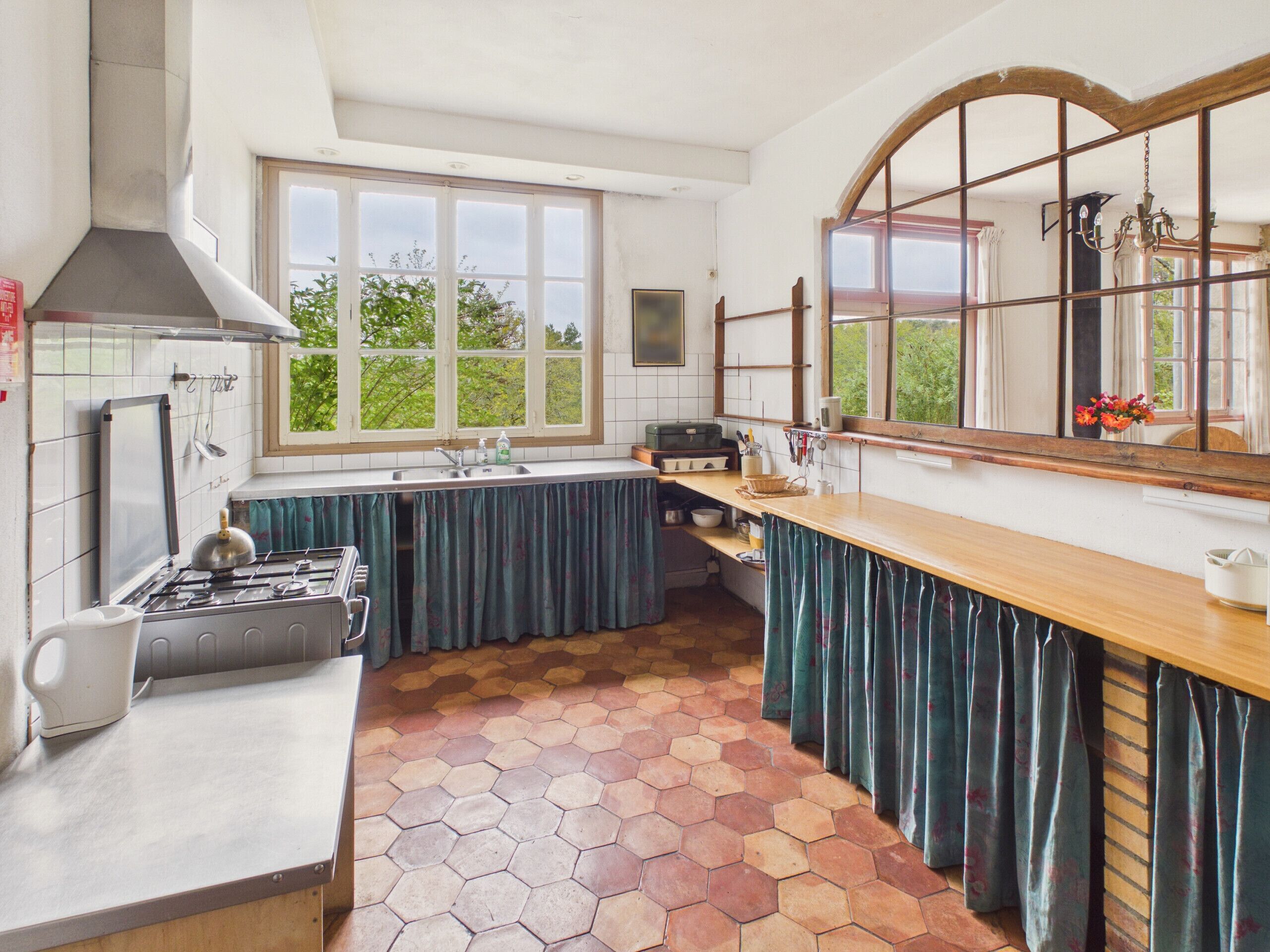 Una cocina con estufa a gas, pileta y ventanas amplias.