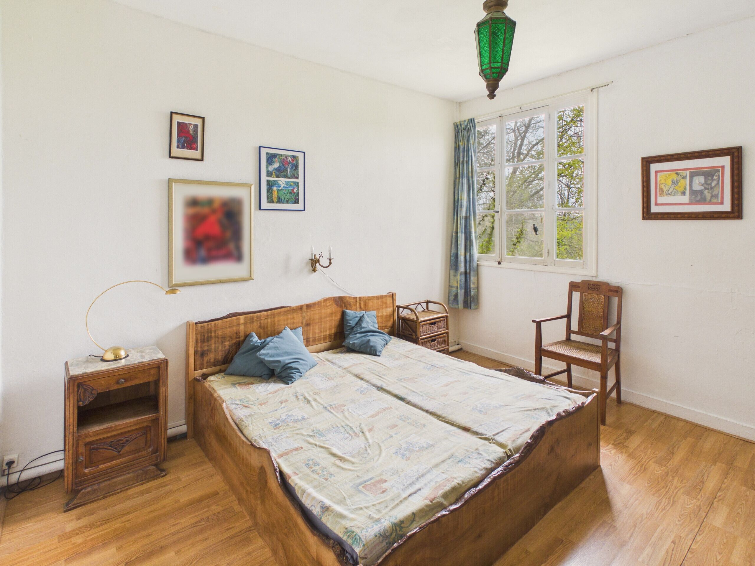 Un dormitorio con una cama de madera, una mesita de noche, una silla y una ventana con cortinas.