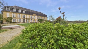 Ein großes, historisches Gebäude mit einer symmetrischen Fassade, einem zentralen Eingang und einem gepflegten Garten im Vordergrund.