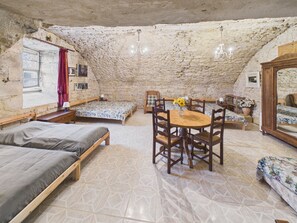 A rustic room with a stone ceiling, a wooden dining table, and multiple beds. - Large home for 9 between nature and heritage (Fanlac)