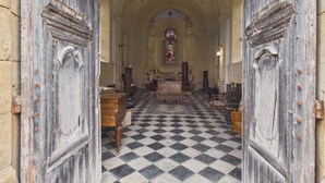 Ein Kircheninneres mit Schachbrettfußboden, Holzbänken und einem Buntglasfenster.