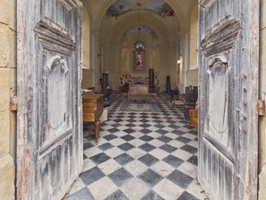 A church interior with a checkered floor, wooden pews, and a stained glass window. - Large home for 9 between nature and heritage (Fanlac)