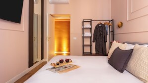 A hotel room with a bed, a TV, a wardrobe, and a mirror. - DEZA| Monti Incanto Boutique Apartment (Roma)
