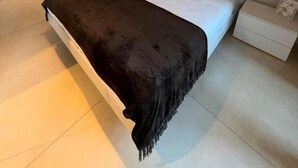 A bedroom with a bed, bedside tables, a wardrobe, and an air conditioning unit.