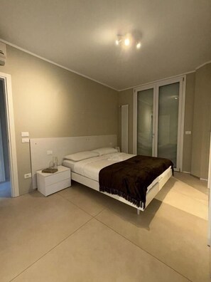 A bedroom with a bed, bedside table, and a sliding glass door.