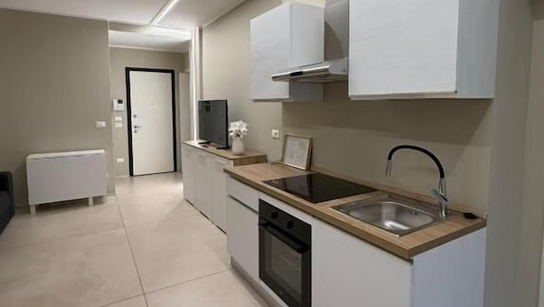 A modern kitchen with white cabinetry, a built-in oven, a sink, and a countertop.