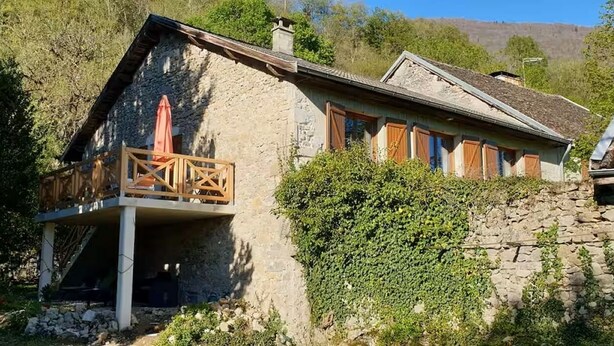 A stone building with a balcony, surrounded by greenery and a mountainous backdrop. - GÏTE DE LA CHAPELLE (Talissieu)