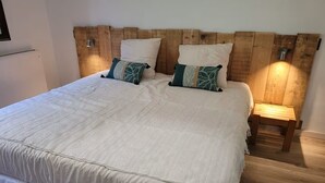 A bed with a wooden headboard, two bedside tables, and a white bedspread. - GÏTE DE LA CHAPELLE (Talissieu)