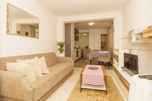 A living room with a sofa, a coffee table, a TV, and a dining area with a table and chairs. - Spacious 35 m² studio apartment for 2 people in Crikvenica (Crikvenica)