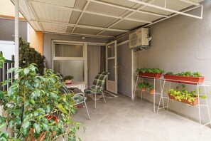 A covered balcony with a chair, potted plants, and a window. - Spacious 35 m² studio apartment for 2 people in Crikvenica (Crikvenica)